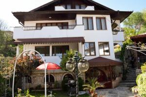 a white house with a red umbrella in front of it at Стаи за гости "КАТИ" Guest rooms "KATI" in Balchik