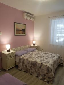Apartments Kurtic في ماكارسكا: غرفة نوم بسرير وطاولتين ومصباحين