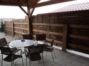 d'une terrasse avec une table, des chaises et une clôture. dans l'établissement Le Gîte du Clos Boisé, à Théziers
