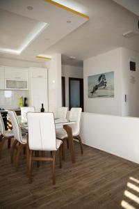 une salle à manger avec des chaises blanches et une table dans l'établissement Apartments Sunny Hill, à Tivat