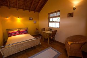 1 dormitorio con cama, mesa y ventana en Jardim do Triângulo - Alojamento local, en Manadas