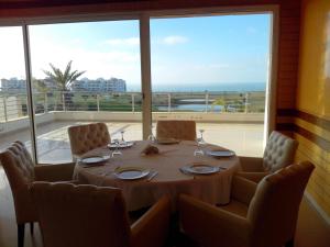 a dining room with a table and chairs and a large window at Marina golf Assila in Asilah