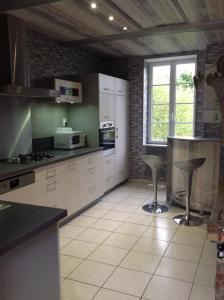 una cocina con armarios blancos y una barra con taburetes en L' ancien pressoir 2, en Pierrefitte-en-Cinglais
