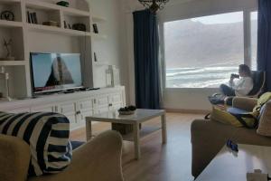 a woman sitting in a living room looking out the window at Playa de Caleta de Famara in Famara