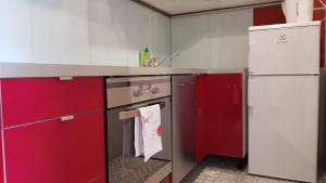 StudioSpanie Apartament Cherry في سوبوت: مطبخ مع دواليب حمراء وثلاجة بيضاء