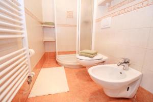 a white bathroom with a toilet and a sink at Alp Apartma in Radovljica