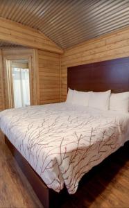a bedroom with a large bed with a wooden wall at Paradise RV & Cabins Resort in Vinton