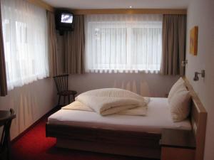 1 dormitorio con 1 cama con sábanas blancas y TV en Apart Kathrin, en Kappl
