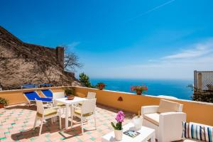 un patio con sedie, tavoli e l'oceano di Casa Chiesa Nuova a Positano