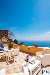 a patio with white chairs and tables and the ocean at Casa Chiesa Nuova in Positano