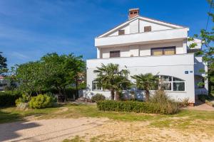 a white house with palm trees in front of it at Apartment Egon in Malinska