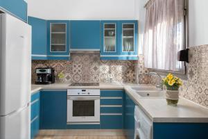 a blue kitchen with white appliances and blue cabinets at villa Diafani, Εirini in Diafani