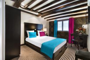 a bedroom with a bed with blue and pink pillows at Hotel Pax Opera in Paris