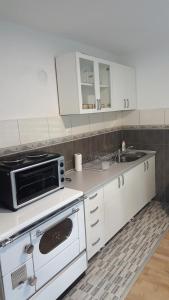 a kitchen with white cabinets and a stove and a sink at Apartman Košuta 2 in Tjentište
