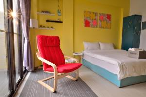 a bedroom with a red chair and a bed at STSP Guest House in Xinshi