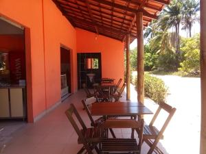 a patio with tables and chairs and an orange wall at Pousada Luar de Monte Cristo in Araripe de Baixo