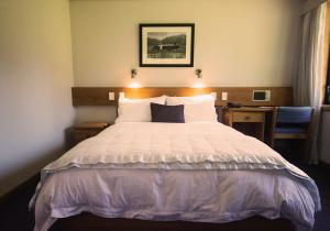 a bedroom with a large bed with white sheets at Alpine Lodge in Saint Arnaud