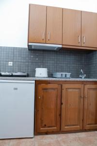 a kitchen with wooden cabinets and a white dishwasher at Panorama Studios in Kefalos