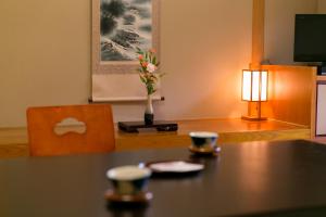 einen Tisch mit zwei Tassen und eine Vase mit Blumen in der Unterkunft Ichinomata Onsen Kanko Hotel in Shimonoseki