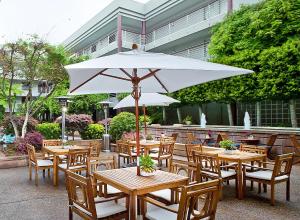 Mesas y sillas de madera con sombrilla blanca en Cupertino Hotel en Cupertino