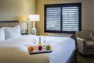 a hotel room with a bed with a tray of fruit and wine glasses at Cupertino Hotel in Cupertino