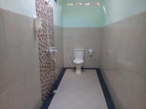 a bathroom with a white toilet in a stall at Krisna Bungalows and Restaurant in Sekotong