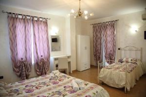 1 dormitorio con 2 camas y cortinas moradas en À La Maison De Gabry, en Vibo Valentia Marina
