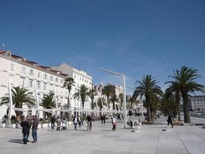 Un gruppo di persone che camminano intorno a una piazza con palme di Apartment Bose a Spalato (Split)