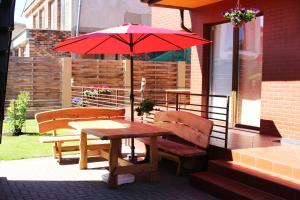 a table and benches with a red umbrella on a porch at Pas Bani in Palanga