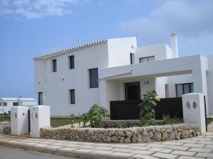 una casa blanca con una pared de piedra delante de ella en Villa Elegante, en Cala Morell