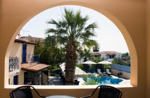 an arched window with a palm tree and a pool at Vanas Apartments in Spetses