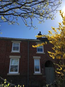 a red brick building with white windows and a cat on the roof at Stable Cottage Lytham in Lytham St Annes