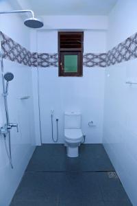 a white bathroom with a toilet and a window at Kottamba Yala Stay & Safari in Tissamaharama
