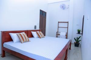 Un dormitorio con una cama con sábanas blancas y una escalera en Yala Leisure Villa & Safari, en Tissamaharama