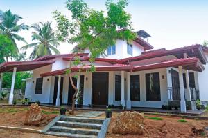 a white house with a tree in front of it at Kottamba Yala Stay & Safari in Tissamaharama