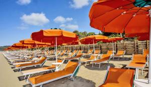 a beach area with chairs, umbrellas and tables at Camping Village Santapomata in Castiglione della Pescaia