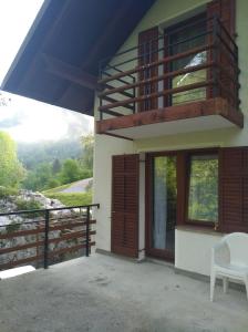 ein Haus mit einem Balkon und einem Stuhl auf einer Veranda in der Unterkunft Apartment Sela in Tolmin