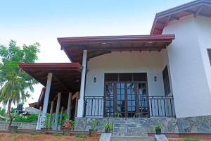 a white house with a porch and a door at Kottamba Yala Stay & Safari in Tissamaharama
