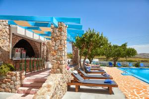 a row of lounge chairs next to a swimming pool at Zorbas Hotel Santorini in Pyrgos