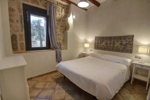 a white bedroom with a bed and a window at Maset del Riu in Valderrobres