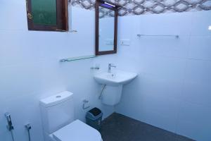 a white bathroom with a toilet and a sink at Kottamba Yala Stay & Safari in Tissamaharama