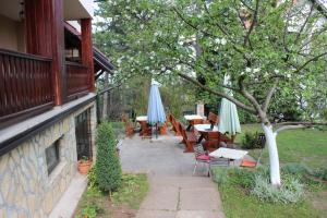 un patio con mesas, sillas y sombrillas en Guest House 3M, en Kaludjerske Bare