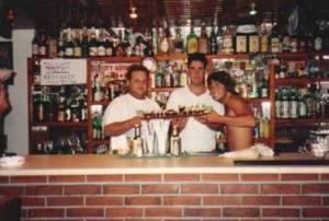 un grupo de personas de pie detrás de un bar con un pastel en Pansion Alexandros, en Pelekas