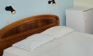 a bed with a wooden head board and a refrigerator at Pansion Alexandros in Pelekas