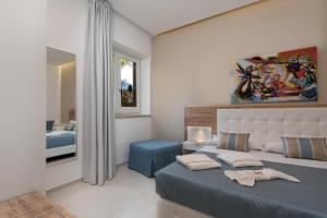a bedroom with a blue bed and a mirror at Artemide Hotel in San Vito lo Capo