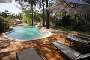 a swimming pool with an umbrella and a table and chairs at Mas du Puech Clapas in Assas