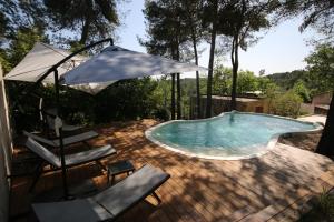 a swimming pool with two chairs and an umbrella at Mas du Puech Clapas in Assas
