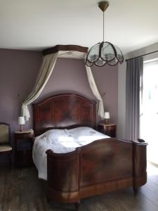 a bedroom with a large wooden bed and a chandelier at BB-hof ter boone in Kapelhoek
