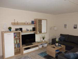a living room with a couch and a flat screen tv at Käptn Seebär in Friedrichskoog-Spitze