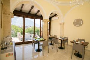 uma sala de jantar com mesas e cadeiras e uma grande janela em B&B Ponte Capograssi em Sulmona